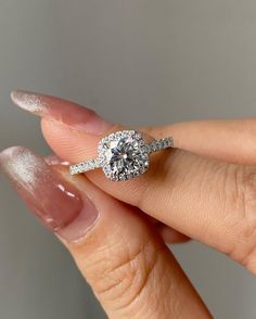 a woman's hand holding an engagement ring with diamonds on the band and side stones