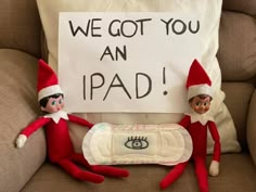 two elfs sitting on a couch with a sign that says we got you an ipad