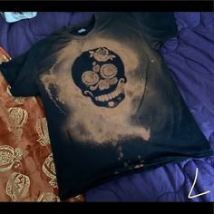 a t - shirt with a skull on it sitting on a bed next to pillows