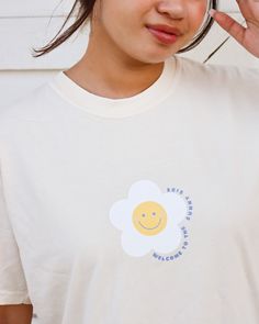 "Happy Daisy Unisex Shirt A gorgeous Ivory T-shirt with a cute smiley daisy design. This tee is unisex, soft, and durable making it perfect for any occasion. If you prefer a more cozy look, go up one size. The front design reads \"welcome to the sunny side\" with a happy daisy graphic in the middle chest area and the back of the shirt reads \"See you on the flip side\" in a gorgeous cobalt blue. This is a great T-shirt for any occasions such as birthdays, anniversaries, Christmas, etc. This desi Playful Spring T-shirt For Everyday, Playful Everyday T-shirt For Spring, Playful White T-shirt With Smiley Face, White Daisy Print T-shirt For Summer, Funny White T-shirt For Spring, Playful White T-shirt For Everyday, Funny Print T-shirt For Spring, Funny Smiley Face T-shirt For Summer, Playful White Top With Smiley Face