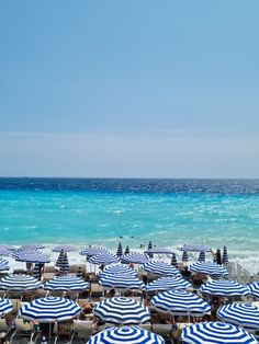 many blue and white umbrellas are on the beach