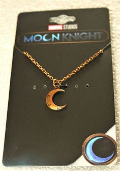 the moon and crescent necklace is on display in front of a card with it's tag