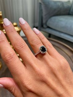 a woman's hand with a ring on it and a couch in the background