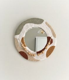 a circular mirror hanging on the side of a wall next to a white cabinet and door