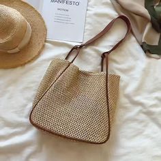 a straw bag and hat on top of a white bed next to a sign that says manfesto