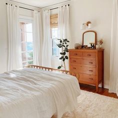 a bedroom with a bed, dresser and window