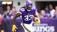 a football player running with the ball in his hand and people watching from the stands