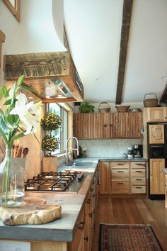 a kitchen with wooden cabinets and white flowers in a vase on the counter top next to an oven