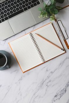 an open notebook, pen and coffee cup on a marble desk