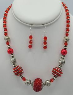 This 18 inch necklace is made from red crystal beads, various types of silver metal beads and bedazzled red beads.  It is completed with a sterling silver jump ring and a sterling silver lobster claw clasp.  The matching earrings are made with 3 of the red crystal beads with silver spacer beads in between and hang a total of 1 1/2 inches in length.   Each earring has a sterling silver earring wire. Red Spacer Beads Jewelry Gift, Red Spacer Beads Jewelry As Gift, Red Crystal Round Bead Necklaces, Red Crystal Round Bead Necklace, Red Crystal Necklace With Round Beads, Red Crystal Beaded Necklaces With Round Beads, Silver Crystal Beaded Necklaces With Spacer Beads, Adjustable Red Jewelry With Silver Beads, Silver Crystal Beaded Necklace With Spacer Beads