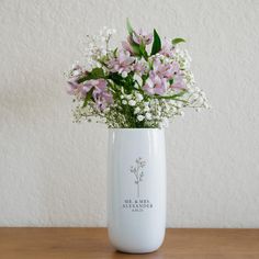 a white vase filled with flowers on top of a wooden table