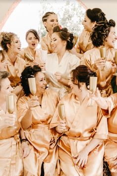 a group of women in gold robes holding champagne flutes