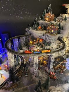 a model train set is shown in front of a christmas scene with trees and lights