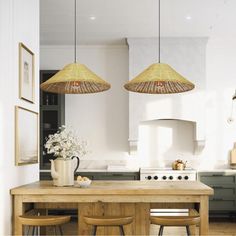 two hanging lights over a kitchen island with stools and table in front of it