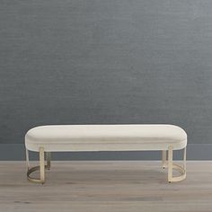 a white bench sitting on top of a hard wood floor next to a gray wall