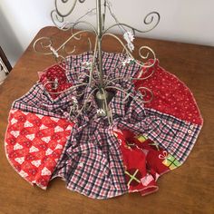 a small tree is decorated with red and white quilts on a wooden table top