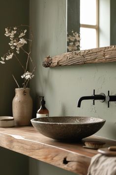 a bowl sink sitting on top of a wooden counter next to a vase with flowers