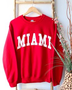 Miami Florida Sweatshirt, Miami Shirt, Miami Crewneck, Miami Sweatshirt for Women, Miami Gifts, Miami Shirts Women * Super soft sweatshirt made of 50% cotton 50% polyester. * Design is high-quality screen printed. * Classic fit - Size up if you want a looser fit. * Unisex sizing - See pictures for size guide. If you have any questions, feel free to message me! Shop Homepage: https://www.etsy.com/shop/peachleafstore/ If you have any issues with your order, please contact me!. *Disclaimer: Since t Red Crew Neck Top For College, Red Long Sleeve Top With Text Print, School Spirit Graphic Print Top For Winter, Varsity Letter Print Top For Winter, Varsity Style Letter Print Top For Winter, Screen Printed Crew Neck Tops, College Style Crew Neck Top With Screen Print, Winter Varsity Top With Letter Print, Winter Varsity Tops With Letter Print