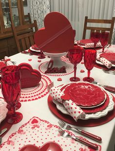 a table set for valentine's day with red and white plates, silverware, and napkins