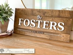 a wooden sign that says the fosters on it next to a potted plant