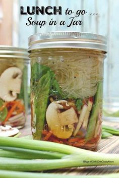 three jars filled with food sitting on top of a wooden table next to green onions