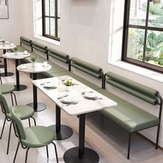 tables and benches in a restaurant with green seats, white tablecloths and plates on them