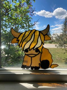 a stained glass cow sitting on top of a window sill