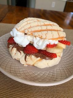 a white plate topped with a sandwich covered in whipped cream and strawberries on top of it