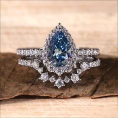 a blue diamond ring sitting on top of a piece of wood next to a leaf