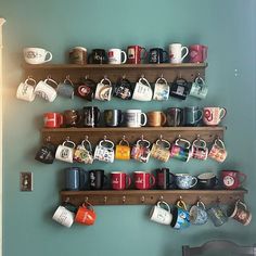 coffee mugs are lined up on wooden shelves above a dining room table and chair