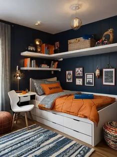 a bedroom with blue walls and white shelving, an orange comforter on the bed