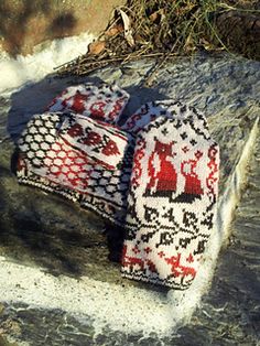 two knitted mittens sitting on top of a rock