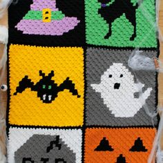 a crocheted halloween blanket with ghost, bat and pumpkins on it's side