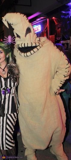 two people in costumes standing next to each other at a halloween party with one person dressed as a cat and the other wearing a costume