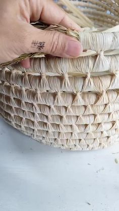 a person holding a woven basket with writing on it