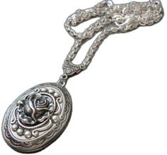 a long silver necklace with a rose on the front and an ornate design on the back