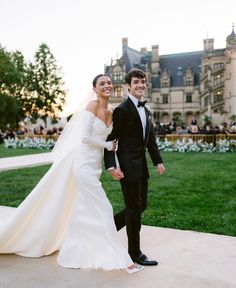 a bride and groom walking in front of a castle