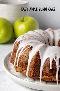 an apple bundt cake with icing on a white plate next to green apples