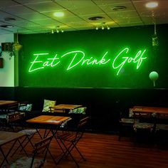 a green neon sign that reads eat drink golf on the side of a wall in a restaurant