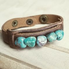 Genuine chunks of African Turquoise is sewn on to a genuine leather cuff with two adjustable snaps. Entire length of bracelet is 3/4" by 9" Adjusts with snaps from Approx. 7.25" to 7.75" Although your bracelet will resemble the photo, each piece is created by hand, so no two are identical. Thank you for visiting The Jewelry Junkie! Adjustable Turquoise Bracelet With Patina, Adjustable Turquoise Bracelets With Patina, Adjustable Turquoise Leather Bracelet In Rustic Style, Adjustable Rustic Turquoise Leather Bracelet, Adjustable Bohemian Leather Cuff Bracelet, Adjustable Southwestern Turquoise Cuff Bracelet, Adjustable Turquoise Southwestern Cuff Bracelet, Southwestern Adjustable Leather Cuff Bracelet, Adjustable Southwestern Leather Cuff Bracelet