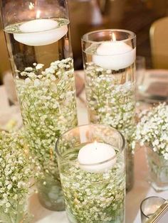 three glass vases filled with flowers and candles