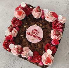 a heart shaped chocolate cake with pink frosting and decorations on it's side