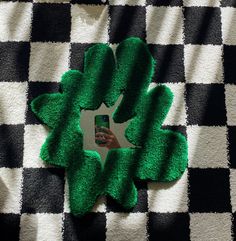 a hand holding a cell phone in front of a black and white checkered blanket