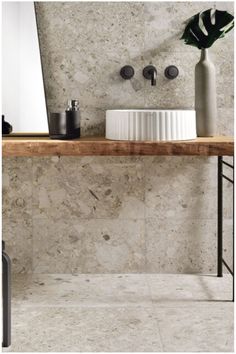 a bathroom with marble walls and flooring next to a wooden shelf holding two vases