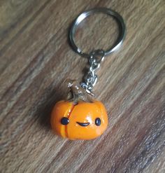 an orange keychain with a smiley face on it sitting on a wooden surface