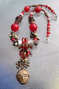 "Thai sterling silver and African beads always seem to enhance each other. This is the story of a little mask who found some colourful and interesting friends. Kenyan brass mask, Thai Hill Tribe silver large bead, small beads and clasp, African brass beads, Bohemian red glass, smokey quartz, small red glass beads.   Length -  20\" Mask pendant 3.5\" Before buying, please CHECK length. Thanks." African Brass Beads, Hill Tribe Silver, Wrap Jewelry, African Beads, Smokey Quartz, Red Glass, Wire Wrap, Wire Wrapped Jewelry, Silver Beads