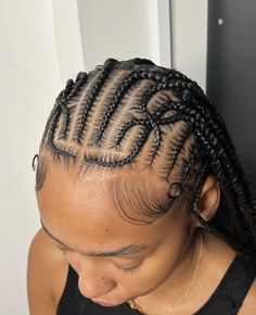 a woman with braids in her hair looking down at the ground while wearing a black tank top