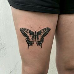 a woman's thigh with a black and white butterfly tattoo on her left leg