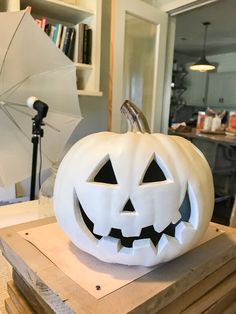 a carved pumpkin sitting on top of a wooden table next to an umbrella and bookshelf