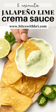 a person dipping guacamole into a bowl with tortilla chips on the side